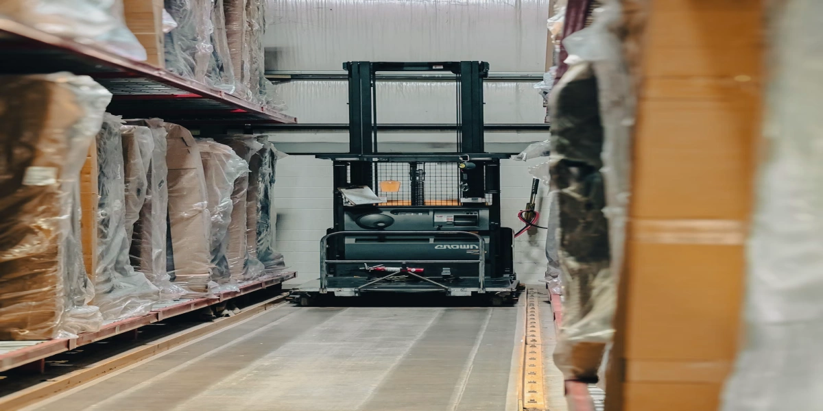 Warehouse aisle with forklift and palletized cartons prepared for fulfillment delivery